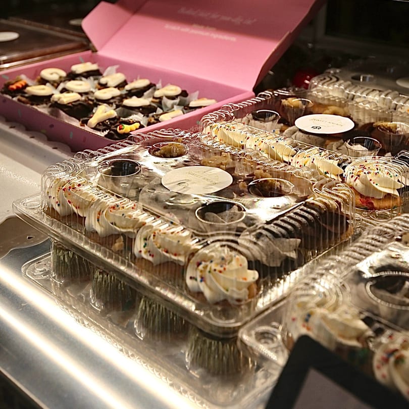 Sweet Kneads cupcakes and brownies in clear plastic containers and a pink box.